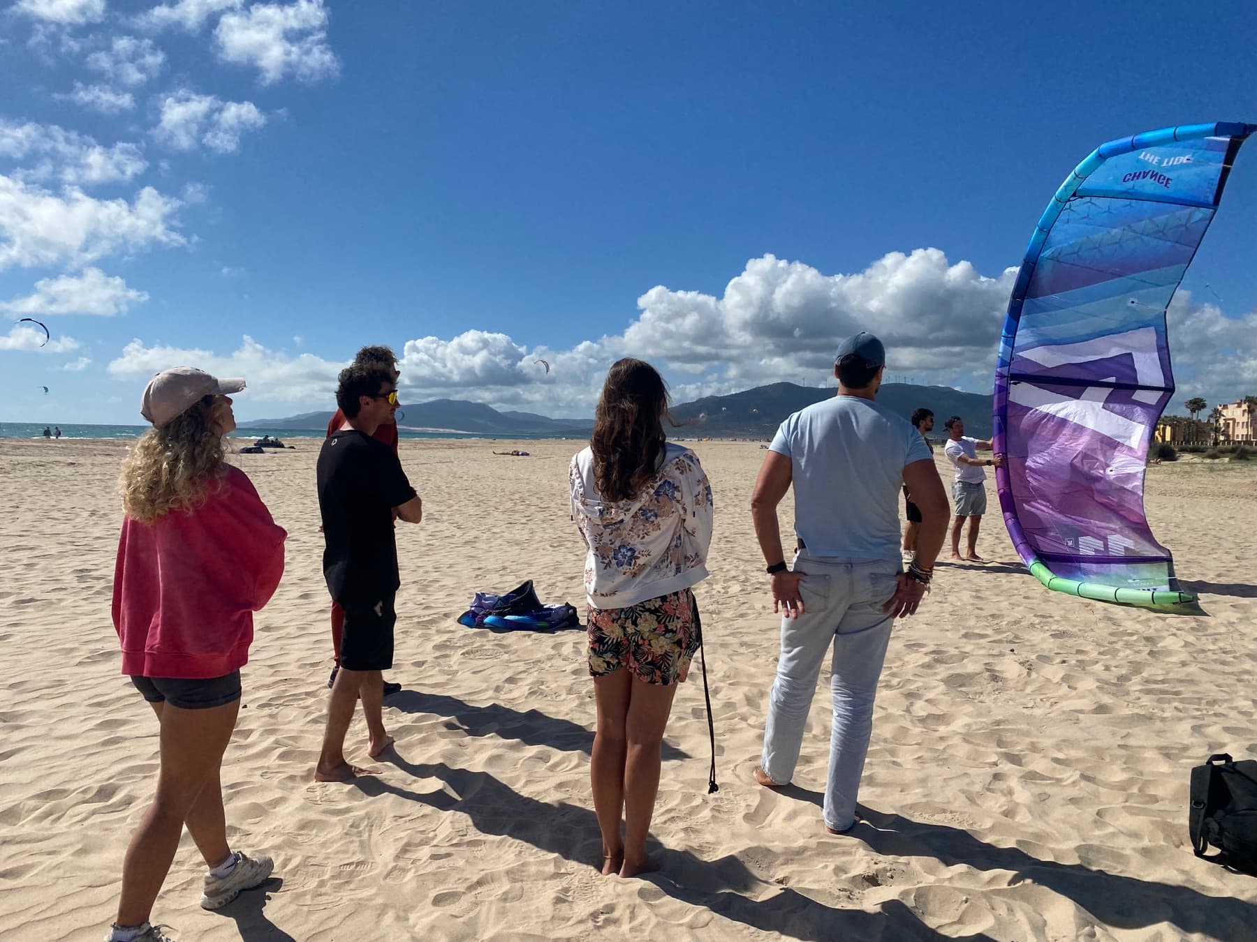 Workshop participants watching a kite handling demonstration on the beach